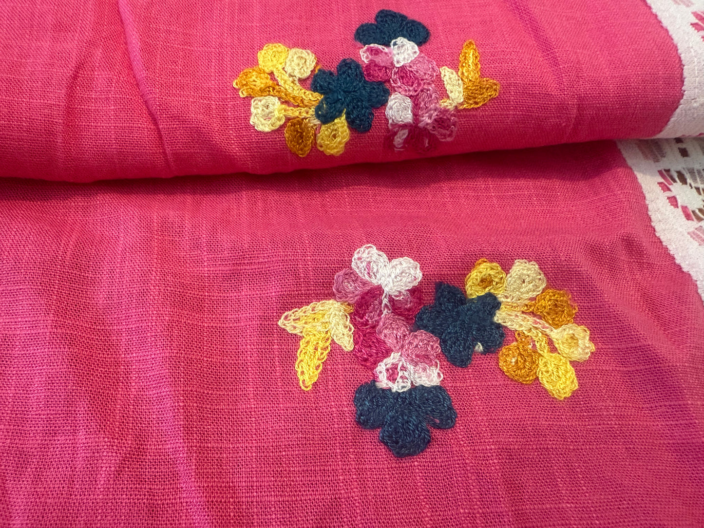Embroidered flower on dark pink background, linen fabric