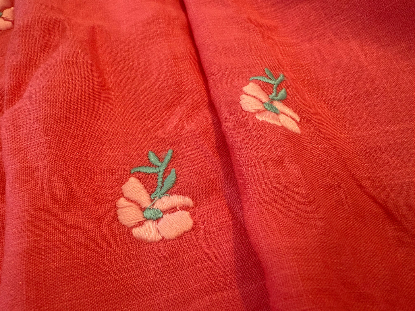 Linen tablecloth with embroidered flowers on coral background